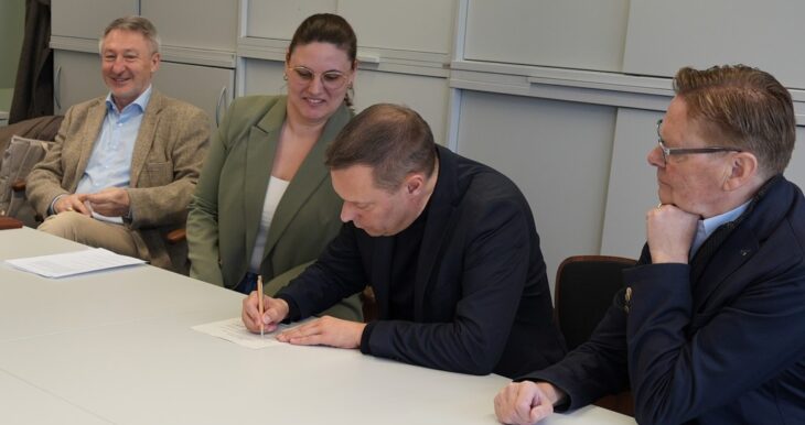 Landrat Armin Kroder unterzeichnet die Bewerbung unter den Augen von (von links) Schulamtsleiter Joachim Schnabel, Projektverantwortlicher Elisa Bräutigam und Landtagsabgeordnetem Norbert Dünkel.