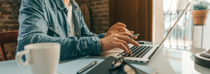 Eine Person arbeitet am Laptop von Zuhause aus.