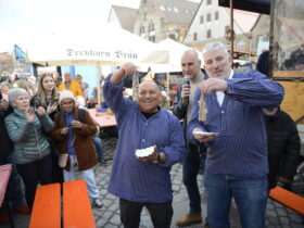 Bürgermeister Thomas Lang (rechts) und Fischhändler Thorsten Niebuhr probieren Matjes, dahinter Moderator Martin Czernan.