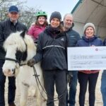Große Freude bei Klientin Sophia auf dem Pferd Rupert, der Reittherapeutin Tina Kokott (4. von links) und bei Sandra Uhl (3. von rechts), der Leiterin des Therapiehofs Leila, bei der Spendenübergabe durch Vertreter der Rummelsberger Diakonie und der Lotte Schopper Stiftung.