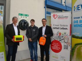 Hewa-Geschäftsführer Harald Kiesl freut sich mit Tobias Buchholz, Projektkoordinator von „Nürnberger Land schockt“, und Bürgermeister Robert Ilg (v. rechts) über den neuen Defi-Standort am Eingang zum Hewa-Kundenzentrum in der Wilhelm-Ulmer-Straße.