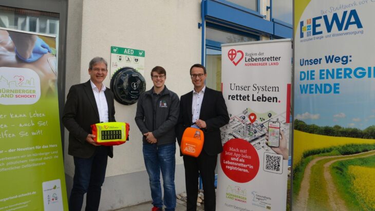 Hewa-Geschäftsführer Harald Kiesl freut sich mit Tobias Buchholz, Projektkoordinator von „Nürnberger Land schockt“, und Bürgermeister Robert Ilg (v. rechts) über den neuen Defi-Standort am Eingang zum Hewa-Kundenzentrum in der Wilhelm-Ulmer-Straße.