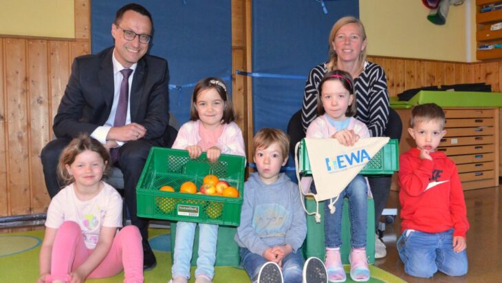 Hewa-Geschäftsführer Harald Kiesl mit Daniela Schindler, Leiterin der Kneipp-Kita „Altstadtzwerge“, und einigen der dortigen Kinder, die jetzt wieder in jeder Schulwoche ihre geliebte gesunde Obstkiste vom Hutzelhof geliefert bekommen.