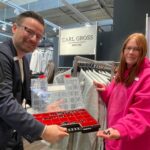 Lisa Herbst überprüft Kleiderbügel mit Etiketten – Ordnung und Qualitätskontrolle gehören zu ihren Aufgaben bei Création Gross in Hersbruck. Angeleitet wird sie von Stefan Hellmer, der ihr auch als „Betriebspate“ für alle Fragen im Betrieb zur Seite steht.