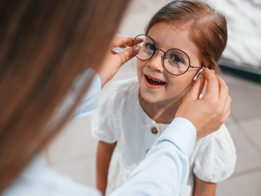 kleines Mädchen mit Brille, die von einer Frau aufgesetzt wird