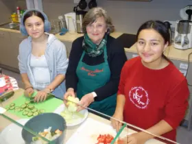 Gemeinsam mit den Ehrenamtlichen bereiten die Schülerinnen und Schüler die Pausenbrote vor.