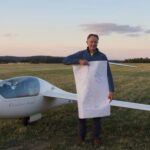 Kurz nach der Landung: Peter Wimmer ist stolz auf seinen ersten 1000-Kilmeter-Flug. Auf dem von Freunden spontan bemalten Plakat steht: „Herzlichen Glückwunsch Peter“ und es ist die 1000 vertikal zu sehen.