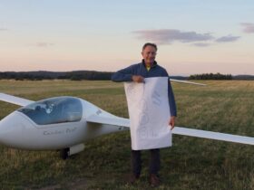 Kurz nach der Landung: Peter Wimmer ist stolz auf seinen ersten 1000-Kilmeter-Flug. Auf dem von Freunden spontan bemalten Plakat steht: „Herzlichen Glückwunsch Peter“ und es ist die 1000 vertikal zu sehen.