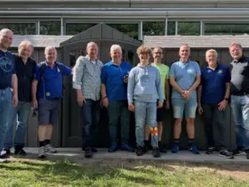 Mitarbeiter und ein jugendlicher Helfer des Blindeninstituts Rückersdorf zusammen mit den Mitgliedern des Lions Club Lauf vor dem fast fertigen Fahrradschuppen.