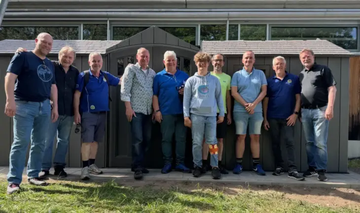 Mitarbeiter und ein jugendlicher Helfer des Blindeninstituts Rückersdorf zusammen mit den Mitgliedern des Lions Club Lauf vor dem fast fertigen Fahrradschuppen.