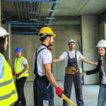 Mehrere Menschen mit Helmen auf einer Baustelle