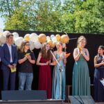 Schulleiterin Birgit Seidl (am Pult) zeichnet die besten Schülerinnen und Schüler des Jahrgangs aus (von links): Eleanor Gheorge, Rahoz Nuri, Moritz Krauß, Alexandru Mágurean, Thea Völkel, Antonia Paul , Milena Lukinskiy und Kristal Singh.