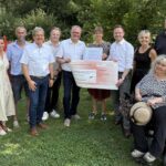 Große Freude bei der Preisverleihung: Bezirkstagspräsident Peter Daniel Forster (5. von rechts) überreicht Alina Stampfl (6. von rechts), Projektleiterin der inklusiven Streuobstwiese, den symbolischen Scheck.