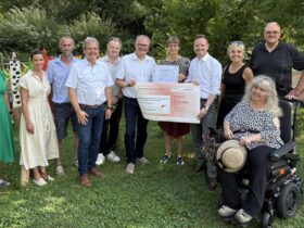 Große Freude bei der Preisverleihung: Bezirkstagspräsident Peter Daniel Forster (5. von rechts) überreicht Alina Stampfl (6. von rechts), Projektleiterin der inklusiven Streuobstwiese, den symbolischen Scheck.