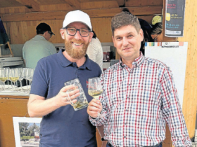 Zwei Herren vor einer Bude mit Getränken in der Hand